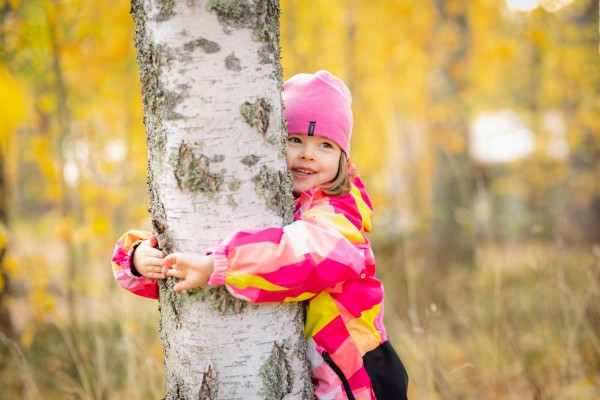 Lapsi halaa puuta syksyisessä metsässä.