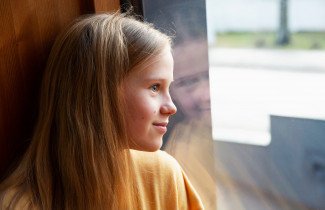 Nuori tyttö katsoo ikkunasta ulos.