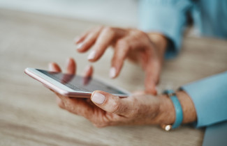 Iäkäs henkilö käyttää älypuhelinta. 