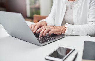 Iäkäs henkilö käyttää kannettavaa tietokonetta.