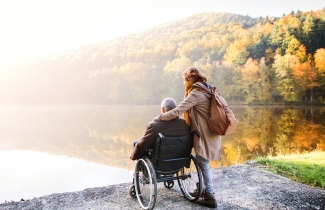 Henkilö istuu pyörätuolissa syysmaisemassa.