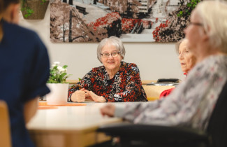 ikääntyneet henkilöt istuvat pöydän ääressä.