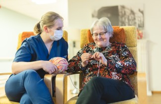 Sote-ammattilainen ja ikääntynyt henkilö neuloo.