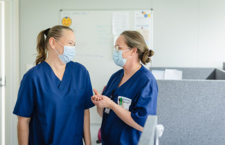 Kaksi ammattilaista keskustelee ja hymyilee toisilleen.