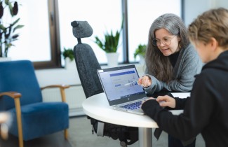 Sosiaalityön ammattilainen opastaa asiakasta tietokoneella.