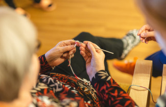 Henkilö istuu tuolissa ja virkkaa.