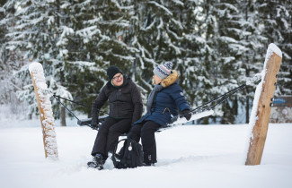 Kaksi henkilöä riippumatossa talvisissa maisemissa.