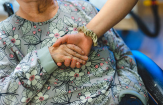 Hoitaja pitelee iäkkään potilaan kättä