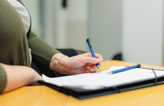 Henkilö tekee muistiinpanoja muistioon kynä kädessä