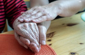Käsi ikäihmisen kädellä 