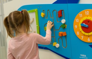 Lapsi leikkii seinällä olevalla värikkäällä aktiivitaululla. 
