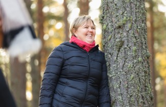 Nainen seisoo metsässä syyssäässä.