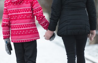 Aikuinen ja lapsi kävelevät käsi kädessä.