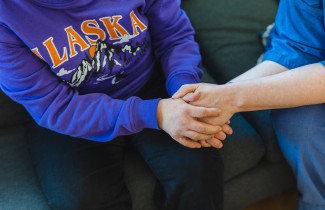 Hyvinvointialueen ammattilaisen ja asiakkaan kädet ovat kietoutuneet yhteen.