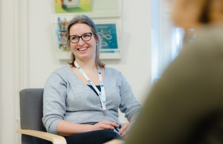 Iloinen ihminen istuu tuolissa vastaanotolla.