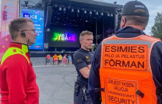 Järjestyksenvalvojia ja pelastajia keskustelemassa suun tapahtuman festivaalilavan edustalla.