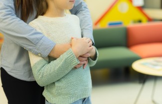 Lapsi ja vanhempi halaavat.