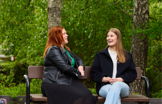 Nuori ja aikuinen juttelevat iloisesta puiston penkillä.