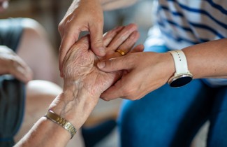 Hoitajan ja hoidettavan kädet.