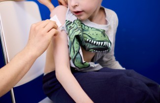 Lapsi saa rokotuksen olkavarteen hoitajan toimesta.