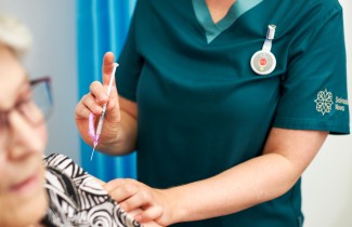 Hoitaja valmistautuu antamaan rokotteen potilaalle.