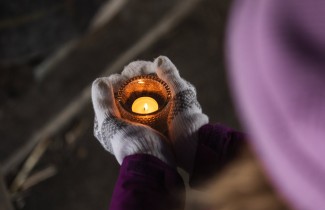 Henkilö pitää käsissään lämpökynttilää lasiastiassa