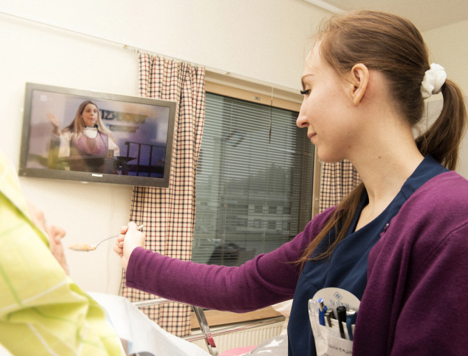 Anne-Mari Laine avustaa ikäihmistä ruokailussa