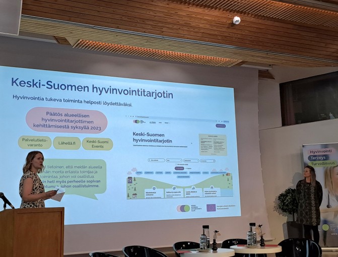 Kaksi esittelijää seminaarilavalla.