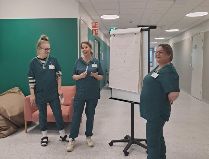 Kolme ammattilaista seisoo fläppitaulun vieressä ja kertoo opiskelijoille arjen rutiineista nuorisopsykiatrialla.