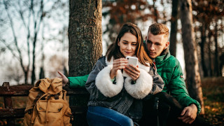 Nuori tyttö ja poika istuvat metsässä. 