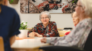 ikääntyneet henkilöt istuvat pöydän ääressä.