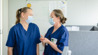 Kaksi ammattilaista keskustelee ja hymyilee toisilleen.