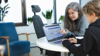 Sosiaalityön ammattilainen opastaa asiakasta tietokoneella.