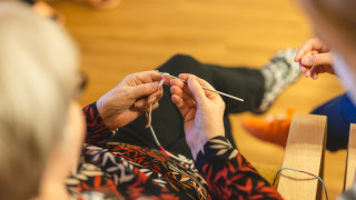 Henkilö istuu tuolissa ja virkkaa.