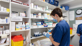 Sote-ammattilainen seisoo selin erilaisten lääkepurkkien edessä.