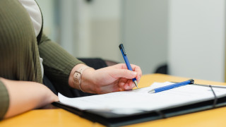 Henkilö tekee muistiinpanoja muistioon kynä kädessä