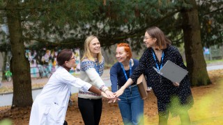 Neljä henkilöä lyövät kättä päälle.