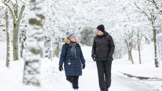 Kaksi henkilöä ulkoilemassa lumisessa maisemassa
