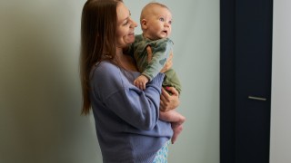 Vanhempi lapsi sylissään.