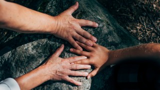 Ihmisten kädet luonnon kivillä.