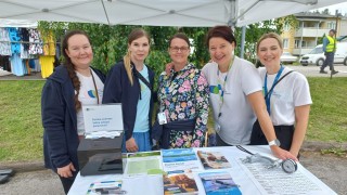 Viisi iloista ihmistä messuteltalla kesällä.