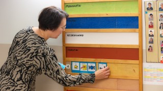 Päivätoiminnan ohjaaja laittaa taululle päivän ohjelman kuvien avulla.