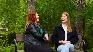 Nuori ja aikuinen juttelevat iloisesta puiston penkillä.