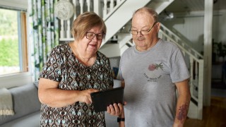 Ikääntynyt pariskunta katsoo yhdessä tablettia.