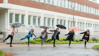 Ihmisiä ulkona sateenvarjojen kanssa.