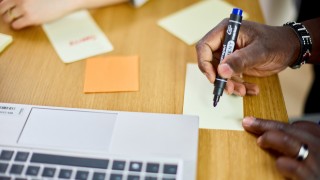 Lähikuva käsistä kirjoittamassa asioita muistilapuille.