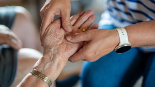 Hoitajan ja hoidettavan kädet.