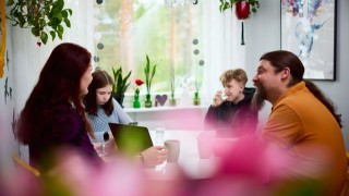 Perhe kotona ruokapöydän ääressä