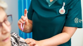 Hoitaja valmistautuu antamaan rokotteen potilaalle.