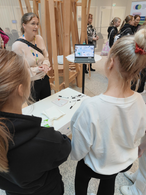 Kaksi opiskelijaa keskustelee laiteturvallisuudesta asiantuntijan kanssa. 